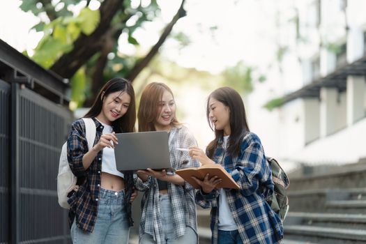 Beautiful young Asian woman college student with friends at outdoors. College student working on the college campus.