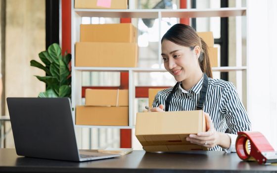Asian girl working with boxes at home office small business owner start up Entrepreneur, small business, SME or self-employed online and delivery concept.