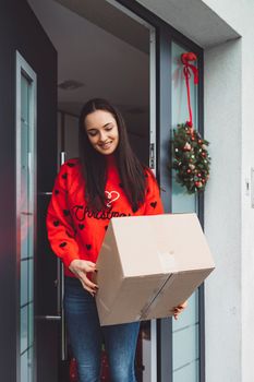 Young caucasian woman wrapping a gift, getting it ready to send in the post. Woman packaging a surprise gift for a family member, packaging it into a brown cardboard box.