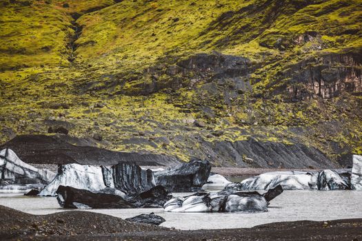 Winter mountains landscape, beautiful view of green mountains and glacier underneath, cold frosty weather, beauty of Iceland nature. High quality photo