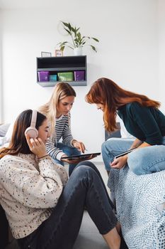 Group of three roommates, college student, young caucasian women, spending time together in their room, studying, talking, having fun, laughing.