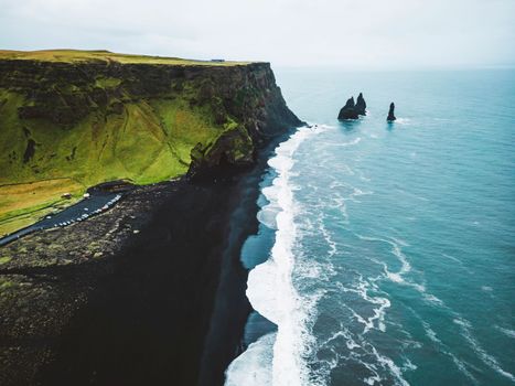 Volcanic Black Sand Beach with a view of Reynisdrangar. Waves crashing on the black sand beach. Vik, Iceland. High quality photo