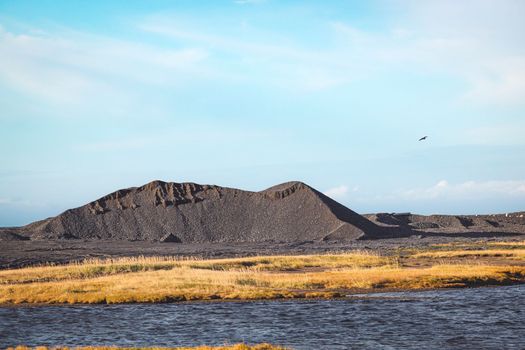 A black volcanic sand dune somewhere in Iceland on a sunny autumn day.