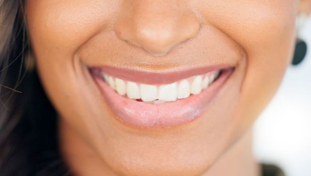 Smiling, beautiful and fresh female face winking feeling fun, silly and playful. Portrait of a happy woman head with perfect skin and healthy teeth. Closeup of a carefree natural beauty with a smile.