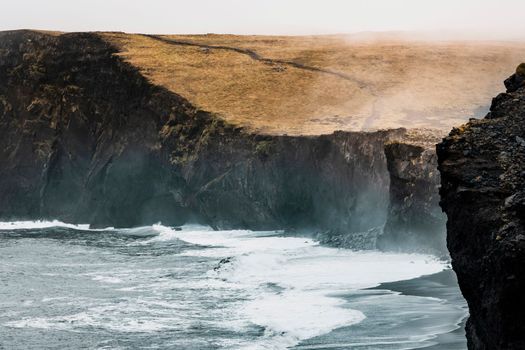 Picturesque autumn Dyrholaey Cape and rock formations view from Reynisfjara ocean black volcanic sand beach. Vik, South Iceland. High quality photo