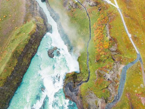 Huge beautiful waterfall Gullfoss, famous landmark in Iceland. River foaming whilst falling down the waterfall, tourist waling by, looking at the waterfall from a view point. High quality photo