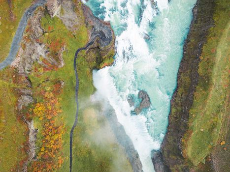 Huge beautiful waterfall Gullfoss, famous landmark in Iceland. River foaming whilst falling down the waterfall, tourist waling by, looking at the waterfall from a view point. High quality photo
