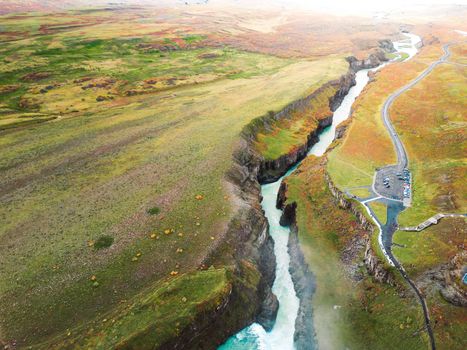 Huge beautiful waterfall Gullfoss, famous landmark in Iceland. River foaming whilst falling down the waterfall, tourist waling by, looking at the waterfall from a view point. High quality photo