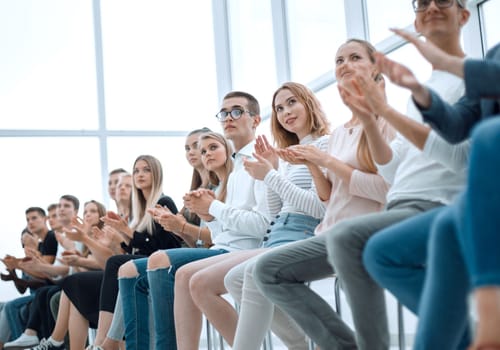 large group of diverse young people sitting in a row and applauding. photo with copy space