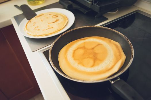 Frying pancakes in a pan on an black induction hob