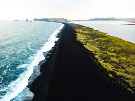 Volcanic Black Sand Beach with a view of Reynisdrangar. Waves crashing on the black sand beach. Vik, Iceland. High quality photo