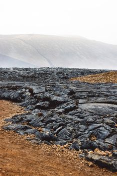 Geldingadalir active Volcano, errupting in 2021 - Fagradalsfjall and 2022 -Meradalir. Still hot lava rocks, steam comping up from the grounds. Dark grey, black volcanic rocks in Iceland. Dramatic view of lava rocks cold cloudy autumn day in Iceland.