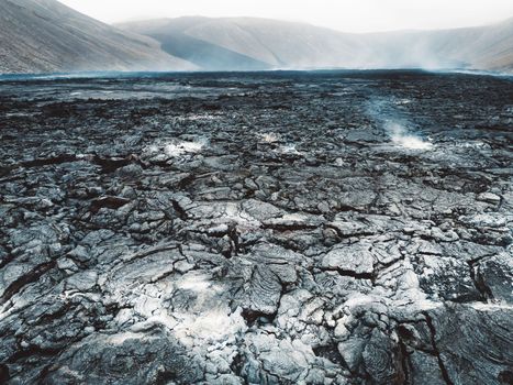 Geldingadalir active Volcano, errupting in 2021 - Fagradalsfjall and 2022 -Meradalir. Still hot lava rocks, steam comping up from the grounds. Dark grey, black volcanic rocks in Iceland. Dramatic view of lava rocks cold cloudy autumn day in Iceland.