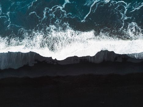 Volcanic Black Sand Beach with a view of Reynisdrangar. Waves crashing on the black sand beach. Vik, Iceland. High quality photo