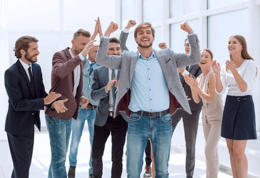happy young businessman standing in front of his business team. success concept