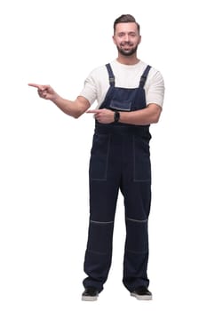 in full growth. smiling man in overalls pointing to a copy of the space . isolated on white