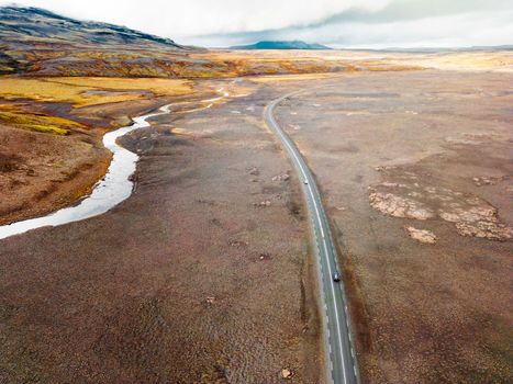 Icelandic highlands, F roads, river crossing. Remote dirt road somewhere in Iceland mainland, surrounded by vibrant green bushes and volcanic lands. A car driving alone on the gravel road.