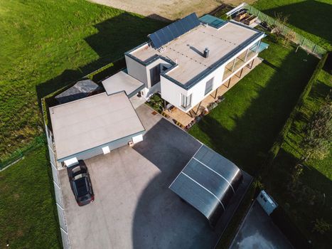 Aerial view of a modern house with solar panels on the roof top. Modern architecture, suburban home, country side living, luxury lifestyle. Renewable energy, solar panels.