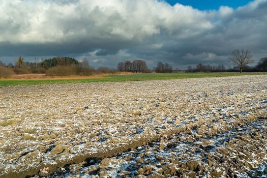Small snow on a plowed field and cloudy sky, eastern Poland