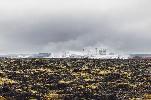 Geothermal Power Plant, hot water power station in Iceland. Steam rolling out of the plant chimneys, red large tubes running across the grounds filled with hot water. Sustainable, energy efficient Cloudy cold autumn day in Iceland.