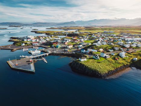 Beautiful aerial view of the Stykkisholmskirkja Harbor with Fishing ships boats at Stykkisholmur town in western Iceland. City view from Sugandisey Cliff with lighthouse. Famous colorful houses. September, autumn 2022.