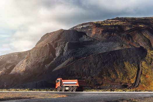 A red truck driving from the red stone quarry in Iceland. Volcanic red stone quarry, exploring Iceland, autumn time.