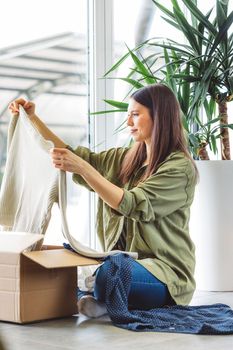 Young caucasian woman receiving a big box of her online orders. Woman opening the package, getting excited to see the stuff she bought. High quality photo