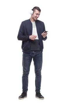 young man with a smartphone listening to music through headphones. isolated on a white