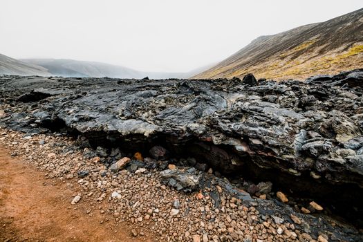 Geldingadalir active Volcano, errupting in 2021 - Fagradalsfjall and 2022 -Meradalir. Still hot lava rocks, steam coming up from the grounds. Dark grey, black volcanic rocks in Iceland. Dramatic view of lava rocks cold cloudy autumn day in Iceland.