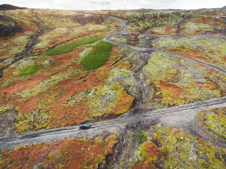 Icelandic highlands, F roads, river crossing. Remote dirt road somewhere in Iceland mainland, surrounded by vibrant green bushes and volcanic lands. A car driving alone on the gravel road.