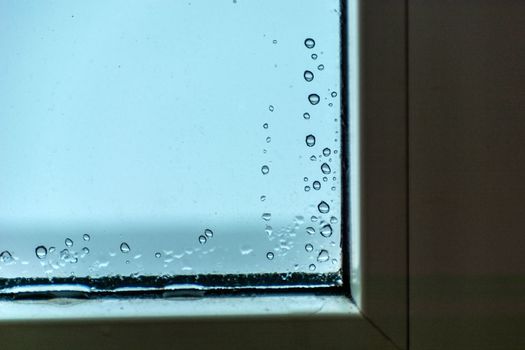 Drops of water on the glass in the corner of the window, winter view