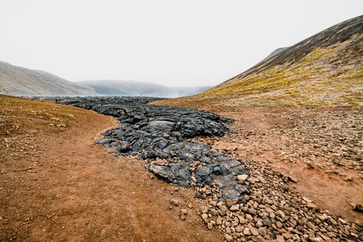 Geldingadalir active Volcano, errupting in 2021 - Fagradalsfjall and 2022 -Meradalir. Still hot lava rocks, steam comping up from the grounds. Dark grey, black volcanic rocks in Iceland. Dramatic view of lava rocks cold cloudy autumn day in Iceland.