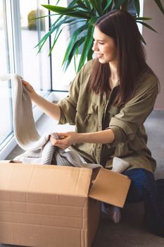 Young caucasian woman receiving a big box of her online orders. Woman opening the package, getting excited to see the stuff she bought. High quality photo