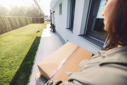 Young caucasian woman receiving a big box of her online orders. Woman opening the package, getting excited to see the stuff she bought. High quality photo