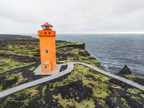 View of orange Svortuloft Lighthouse by the sea in West Iceland highlands, Snaefellsnes peninsula, View Point near Svortuloft Lighthouse. Spectacular black volcanic rocky ocean coast with cave arch and towers. High quality photo