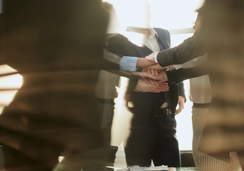 group of young business people joining their palms over a work Desk. concept of teamwork.