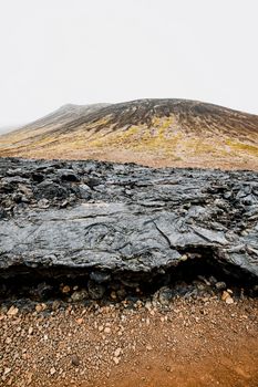 Geldingadalir active Volcano, errupting in 2021 - Fagradalsfjall and 2022 -Meradalir. Still hot lava rocks, steam comping up from the grounds. Dark grey, black volcanic rocks in Iceland. Dramatic view of lava rocks cold cloudy autumn day in Iceland.