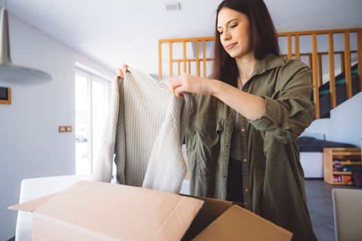 Young caucasian woman receiving a big box of her online orders. Woman opening the package, getting excited to see the stuff she bought. High quality photo