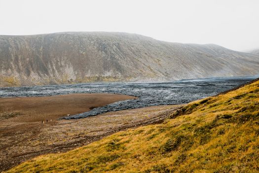 Geldingadalir active Volcano, errupting in 2021 - Fagradalsfjall and 2022 -Meradalir. Still hot lava rocks, steam comping up from the grounds. Dark grey, black volcanic rocks in Iceland. Dramatic view of lava rocks cold cloudy autumn day in Iceland.