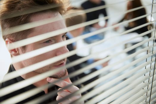 close up. young businessman looking through an office window. business concept.