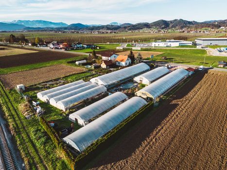 Aerial view over garden center in the country side. Agricultural fields down bellow. Country side life.