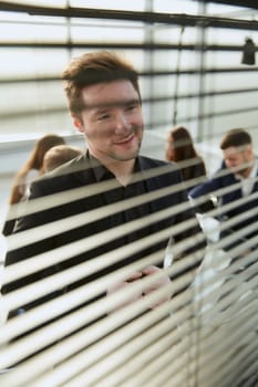 close up. smiling employee looking through office blinds . business concept.