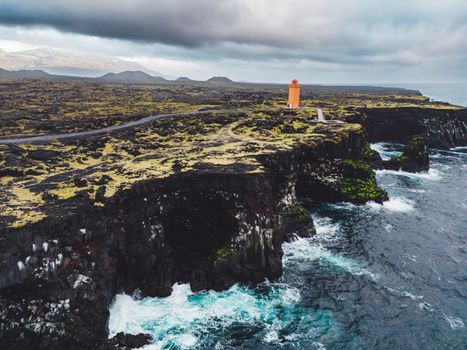 View of orange Svortuloft Lighthouse by the sea in West Iceland highlands, Snaefellsnes peninsula, View Point near Svortuloft Lighthouse. Spectacular black volcanic rocky ocean coast with cave arch and towers. High quality photo