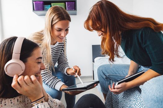 Group of three roommates, college student, young caucasian women, spending time together in their room, studying, talking, having fun, laughing.