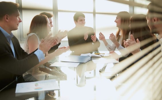 through the blinds. business team applauds sitting at the office table . the concept of success.