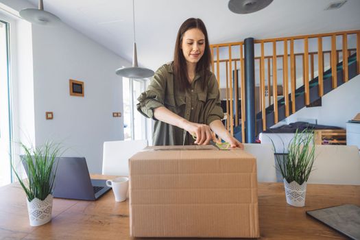 Young caucasian woman receiving a big box of her online orders. Woman opening the package, getting excited to see the stuff she bought. High quality photo