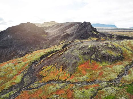 Icelandic highlands. Remote lands somewhere in Iceland mainland, surrounded by vibrant green bushes and volcanic lands. Volcanic rock formations, small mountains.