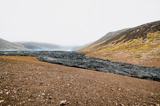 Geldingadalir active Volcano, errupting in 2021 - Fagradalsfjall and 2022 -Meradalir. Still hot lava rocks, steam comping up from the grounds. Dark grey, black volcanic rocks in Iceland. Dramatic view of lava rocks cold cloudy autumn day in Iceland.