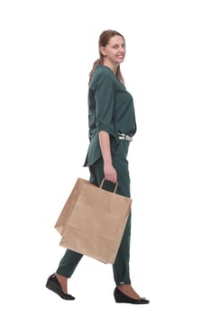 Full length side view of happy young woman walking with shopping bags isolated over white background