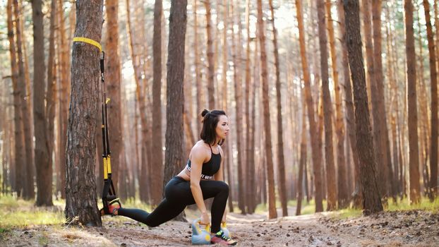 Beautiful, athletic, sexy young woman, coach, instructor, performs exercises, doing exercises. In pine forest, in summer, in sun rays. High quality photo